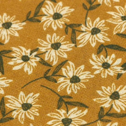 A close-up of a fabric pattern featuring white daisy flowers with dark green centers and stems on a warm mustard-yellow background.