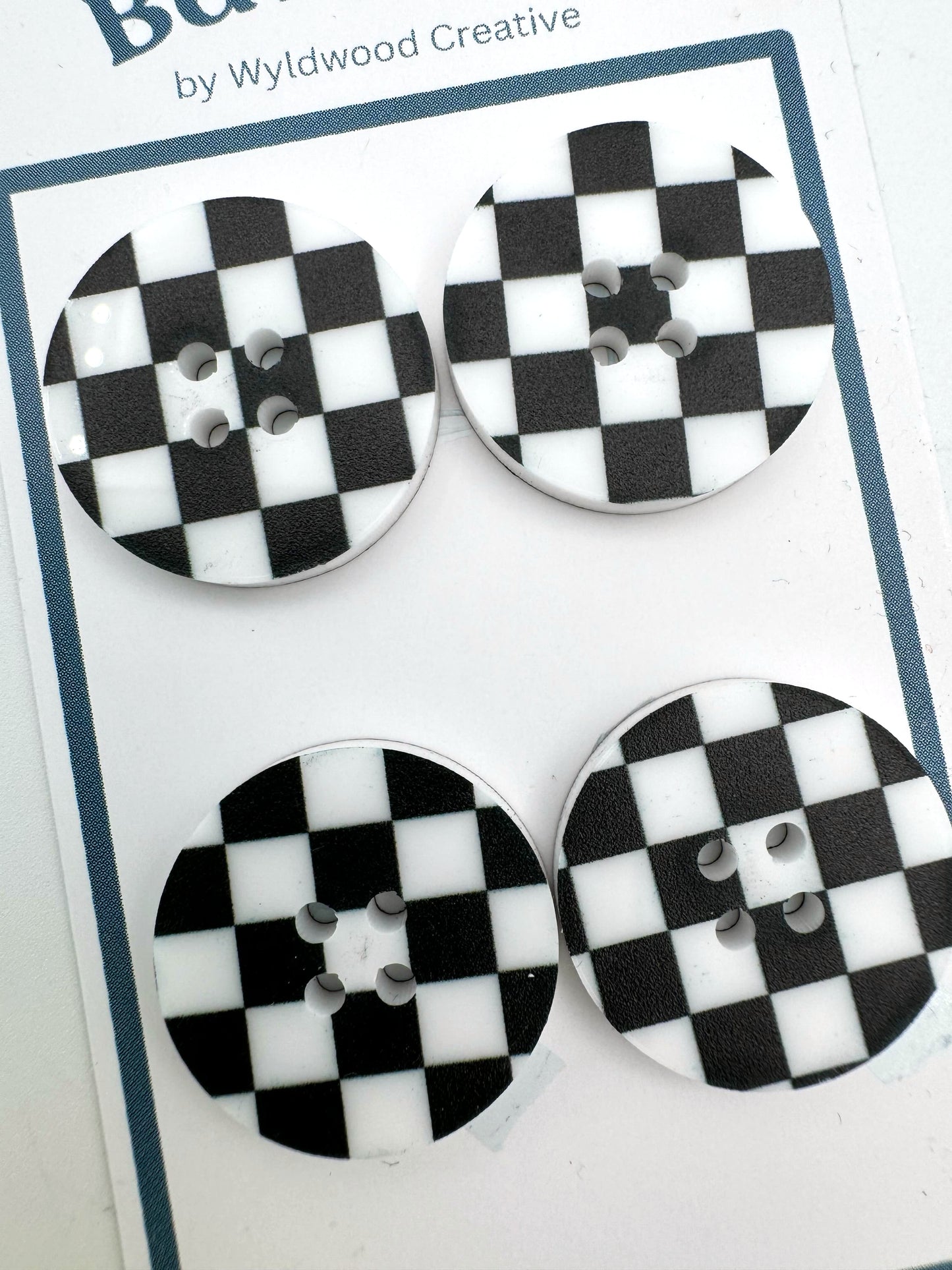 Close up of a set of 4 checkered buttons on a white background