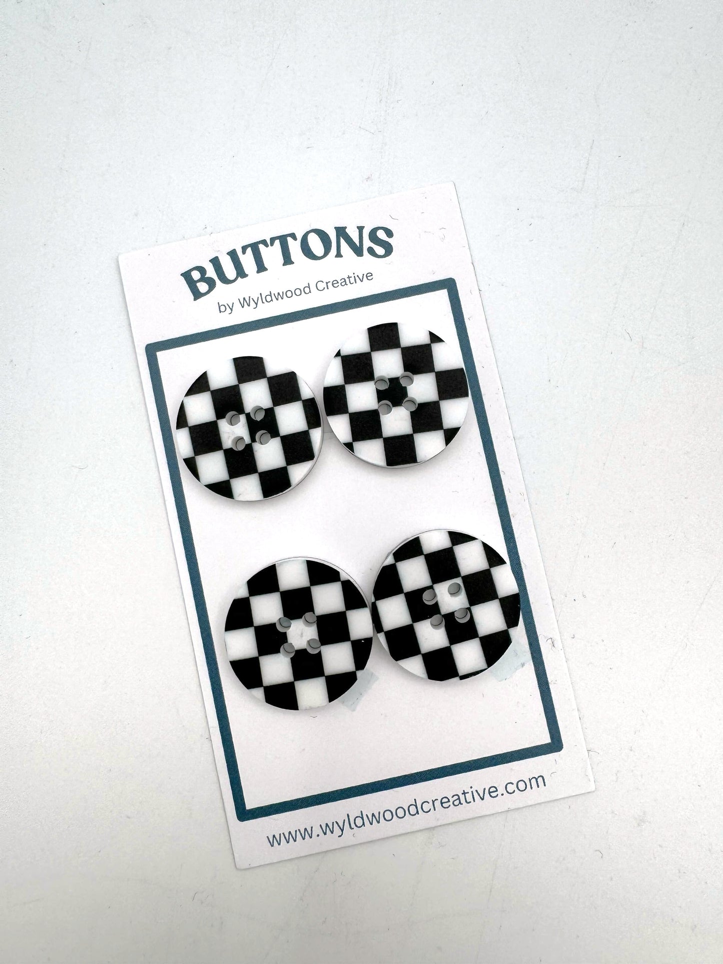 A set of 4 checkered buttons on a paper card against a white background