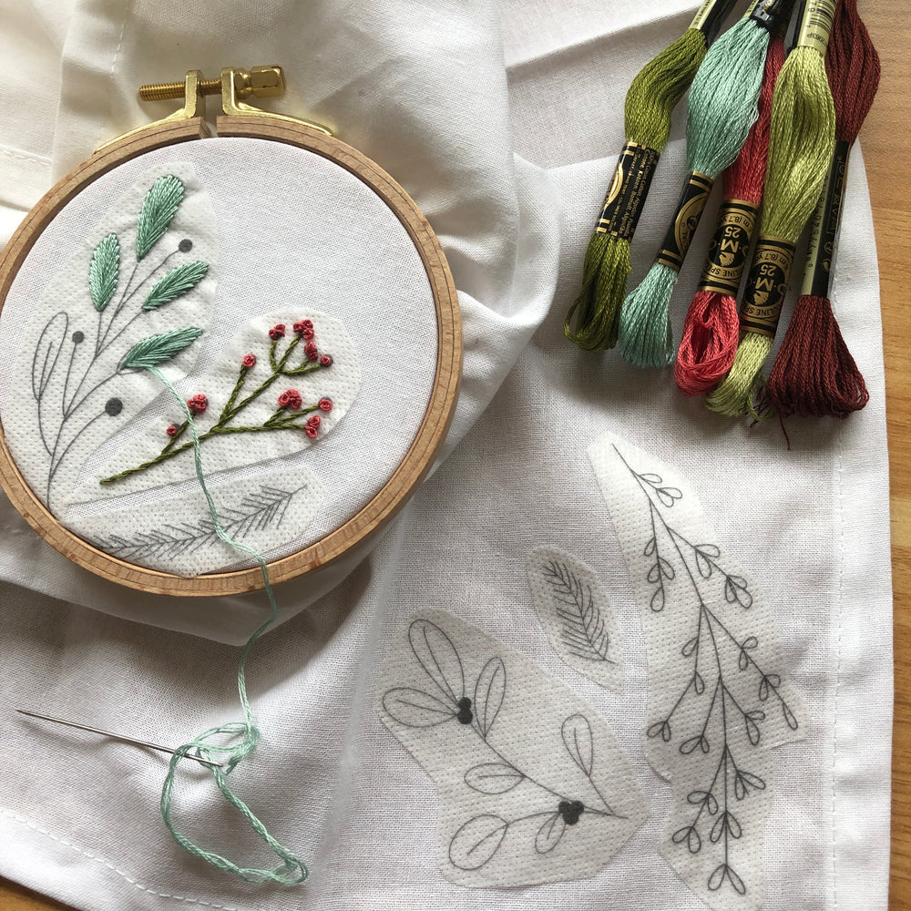 embroidered napkins in hoop with skeins of embroidery floss