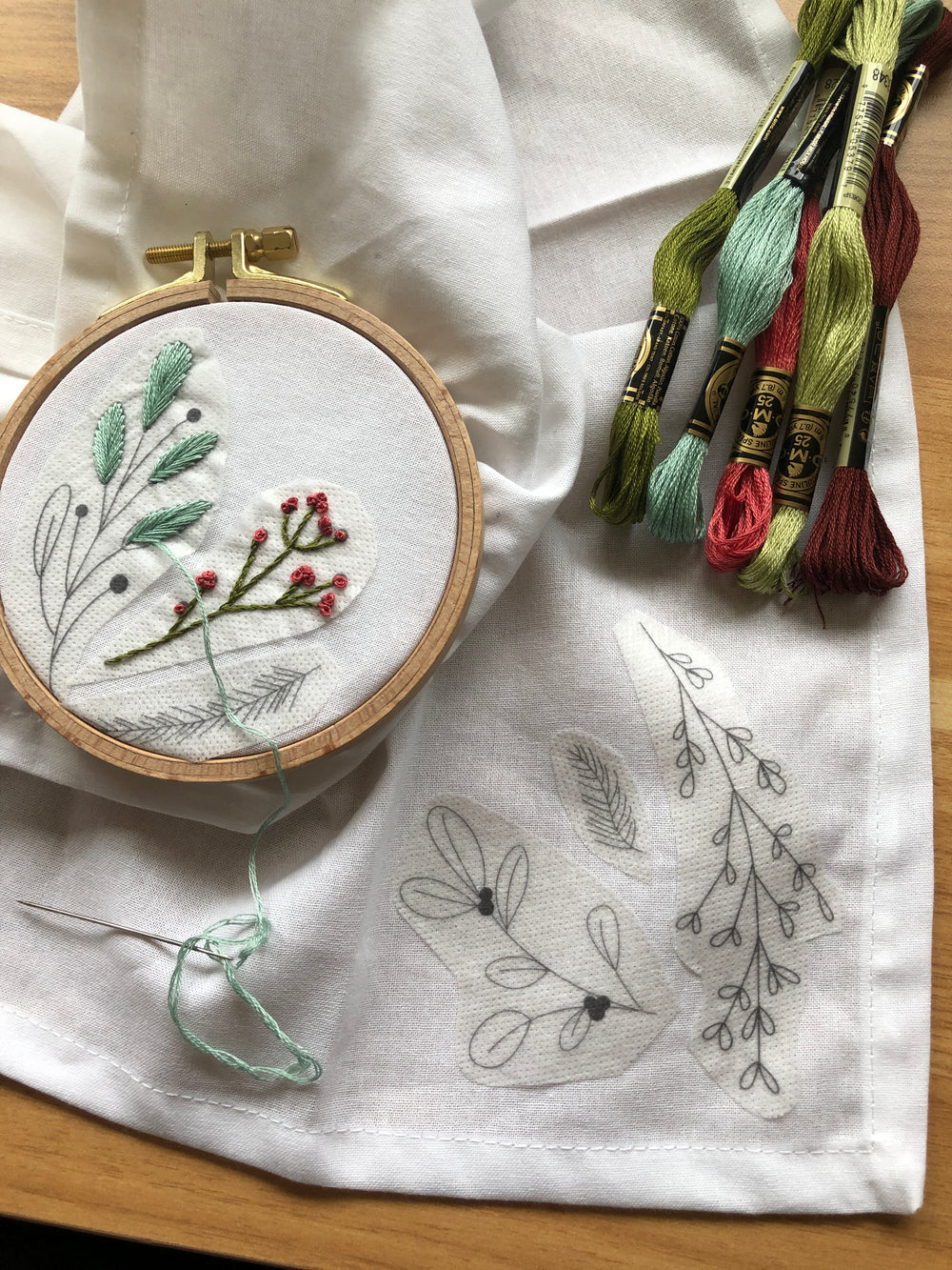 embroidered napkins in hoop with skeins of embroidery floss