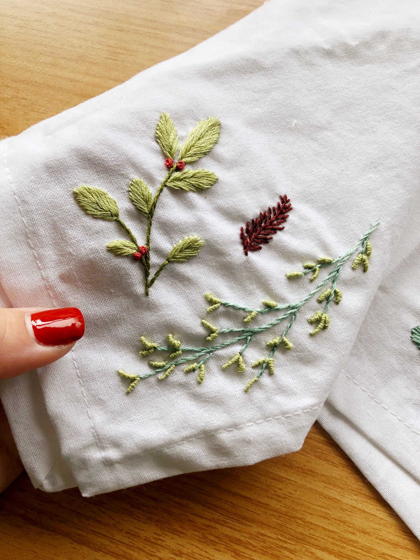 a hand holding Winter themed embroidered foliage 