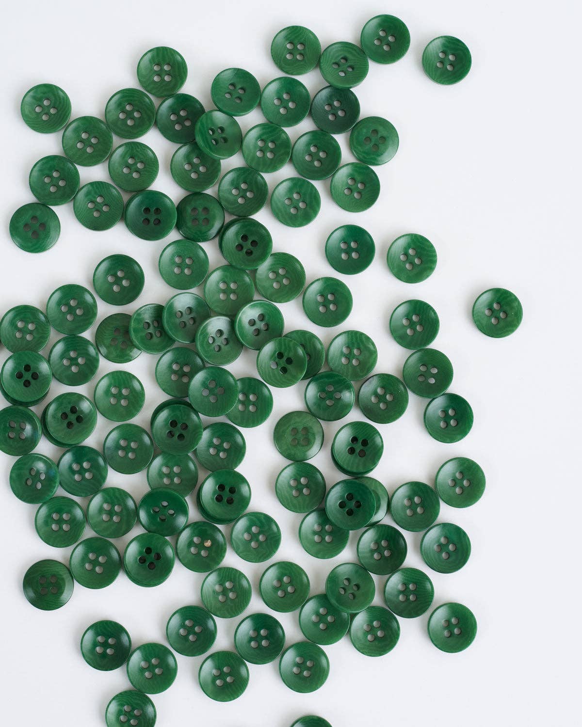 Multiple green 1/2” buttons scattered on a white bacckground