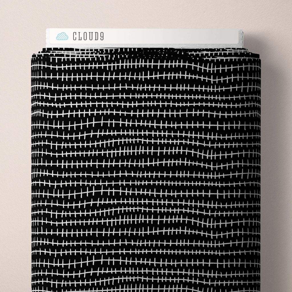 a bolt of fabric featuring sketched, hand-drawn dashed lines arranged in wavy horizontal rows across a black background with white accents against a white background