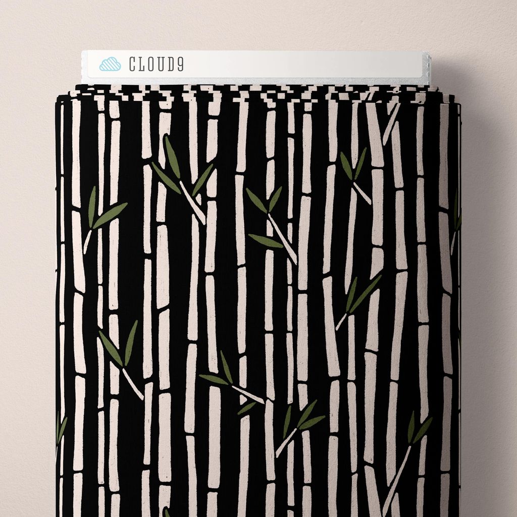 A bolt of fabric featuring a hand-drawn bamboo pattern in white against a black background all against a white background