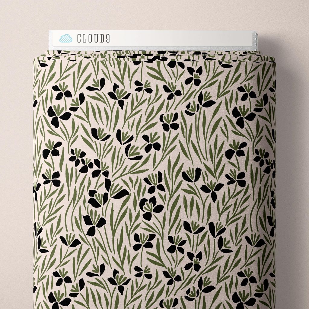 A bolt of fabric featuring sketched wildflower blooms and grassy leaves scattered across a cream background with black and olive green accents against a white background.