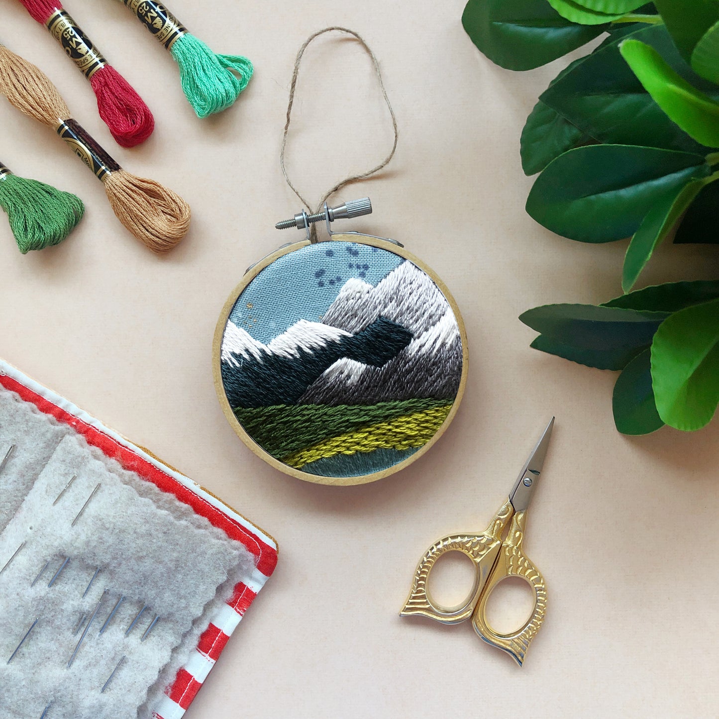 3 inch ornament embroidered to make a Pacific Northwest scene with snow capped mountains and greenery - made at a class at Wyldwood Creative in Renton.