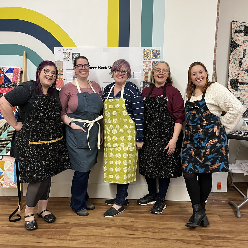 5 class participants wearing their new Sam Aprons sewn in a beginner sewing class at Wyldwood Creative in Renton