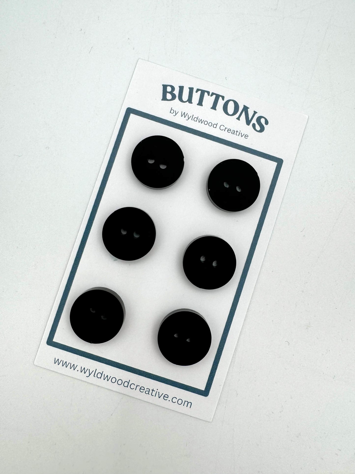 a set of 6 black buttons on a paper card against a white background