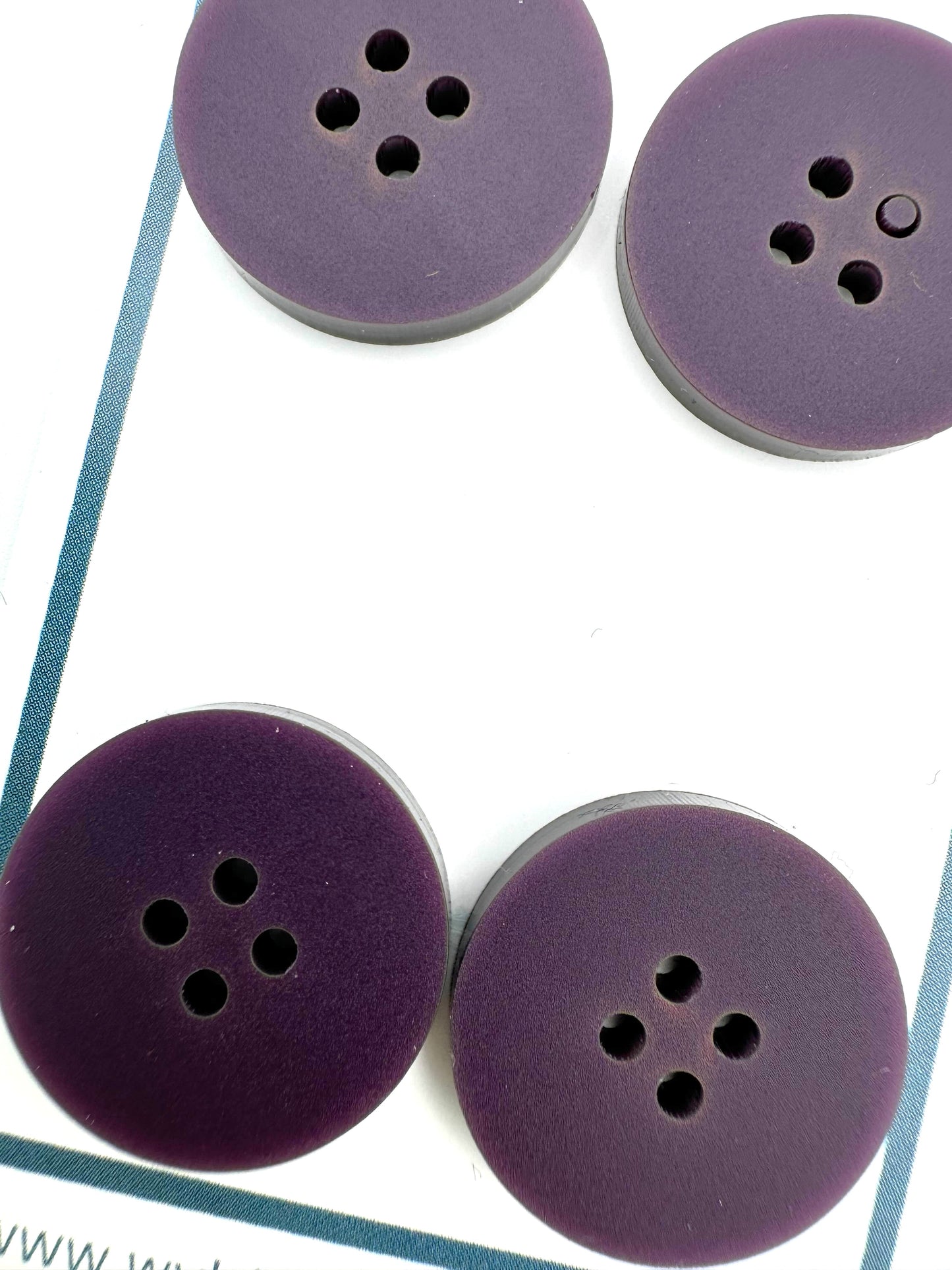 a close up of a set of 4 dark purple buttons on a white card