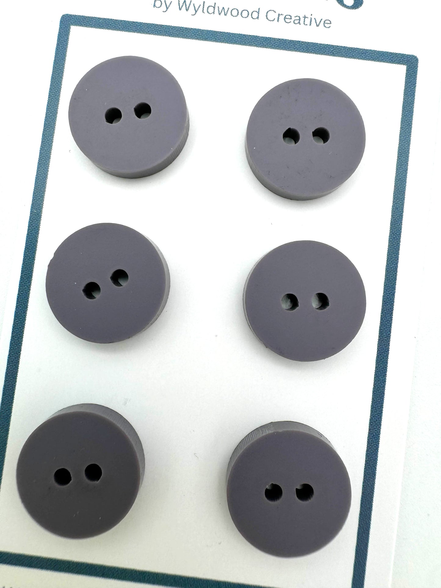 a close up of a set of 6 purple buttons on a paper card