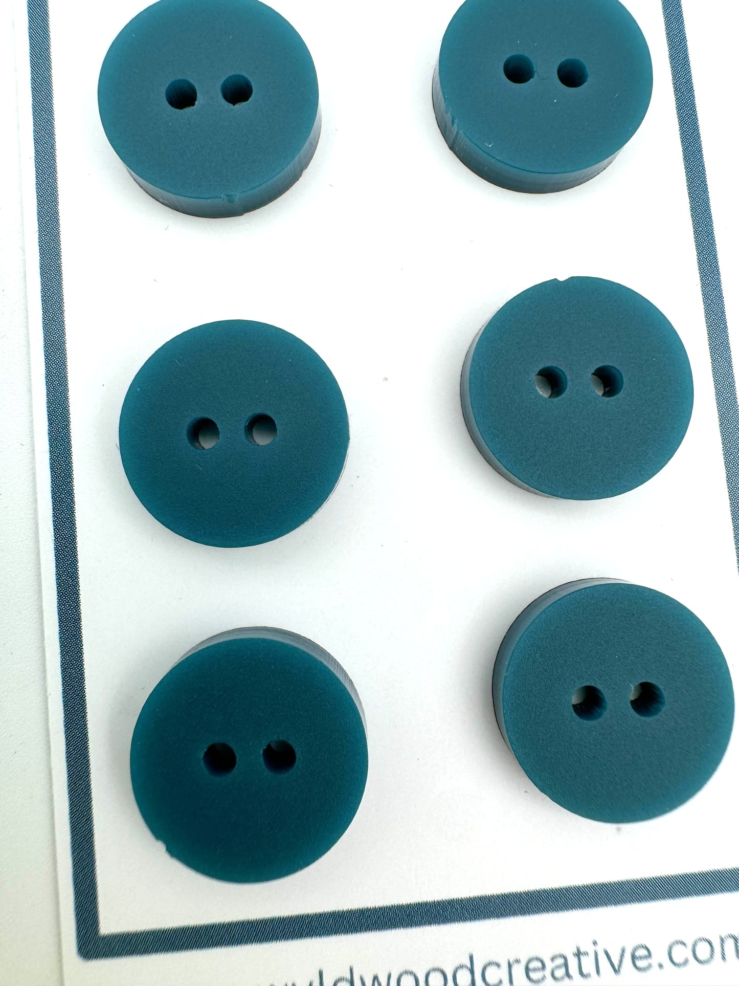 a close up of a set of 6 teal buttons on a paper card