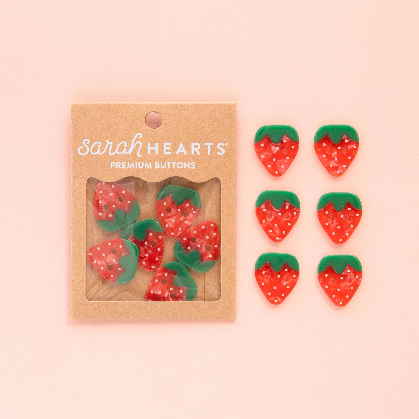 Two sets of 6 strawberry buttons, one in a package, one set arranged on a pink background