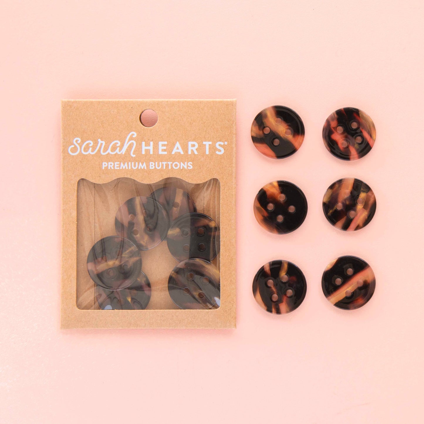 two sets of 6 tortoise shell buttons - one set in a paper package, the other set loose against a light pink background