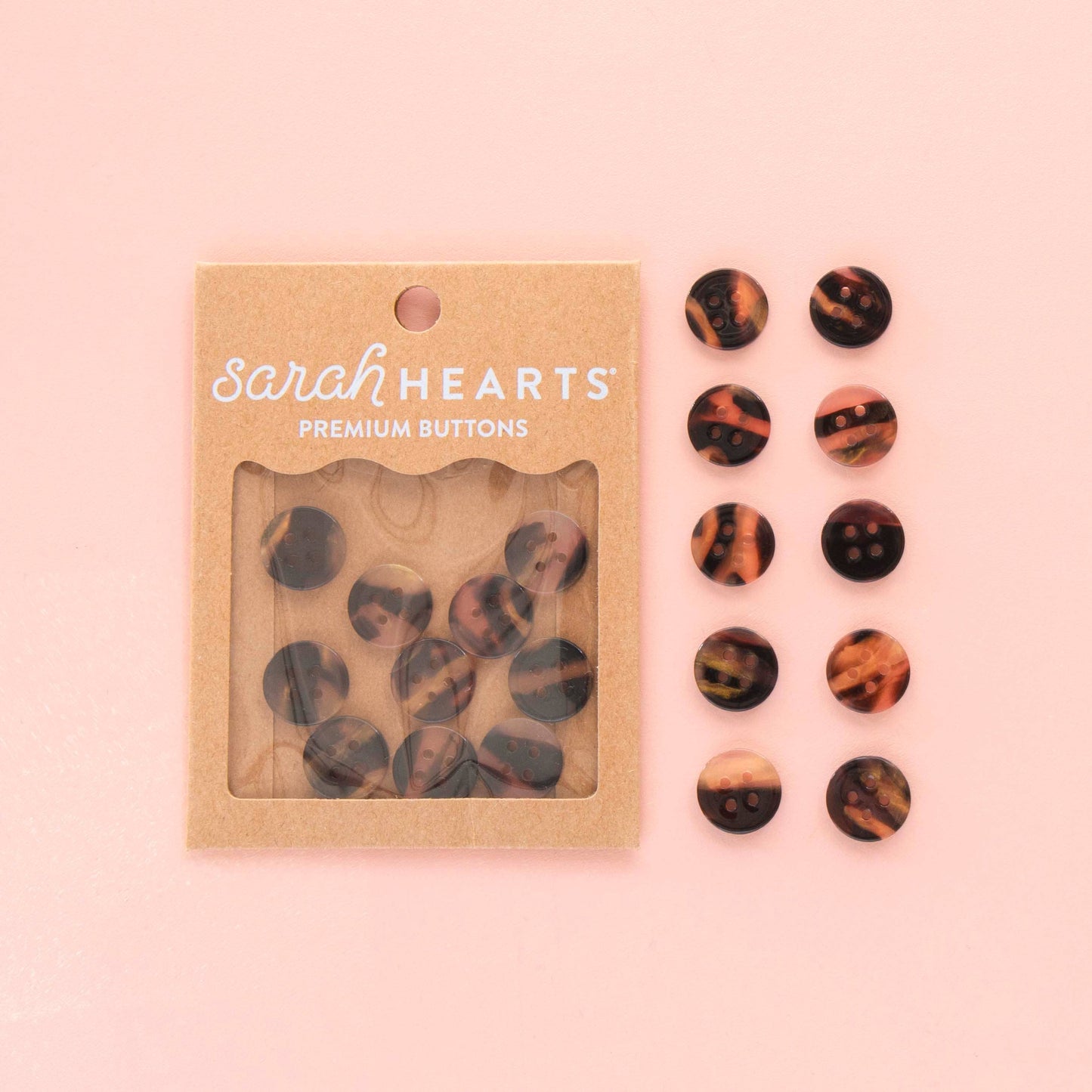 Two sets of 10 tortoise shell buttons, one set in a paper packaging, the other set laid out on a light pink background