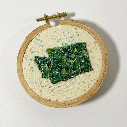 Beaded ornament with a Washington State design beaded in all greens, still in an embroidery loop from a crafting class at Wyldwood Creative in Renton.