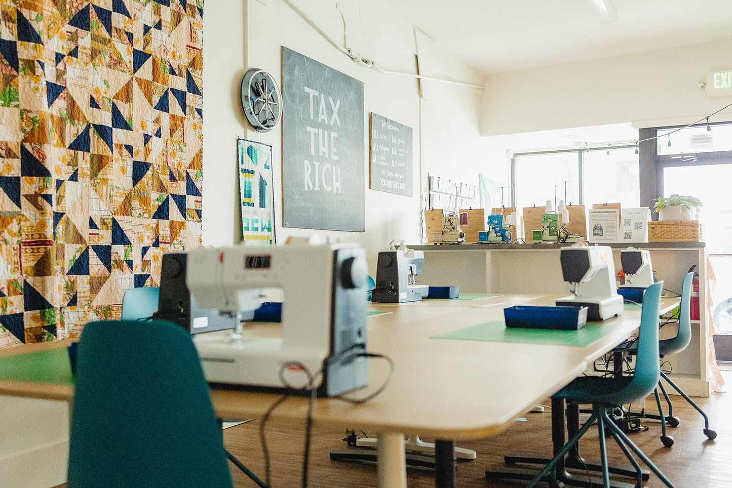 Side angle photograph of the class learning space with sewing machines, sergers, and other tools at Wyldwood Creative in Renton.