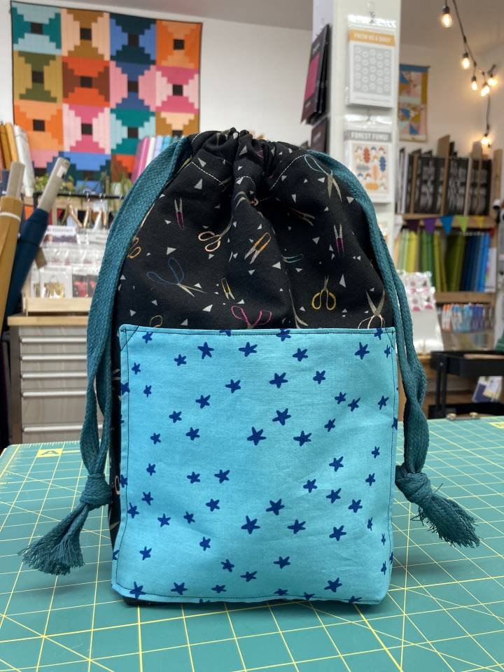 Drawstring bag with blue stars fabric and sewing scissors fabric, sewing with quilting cotton squares in a beginner sewing class in Renton at Wyldwood Creative