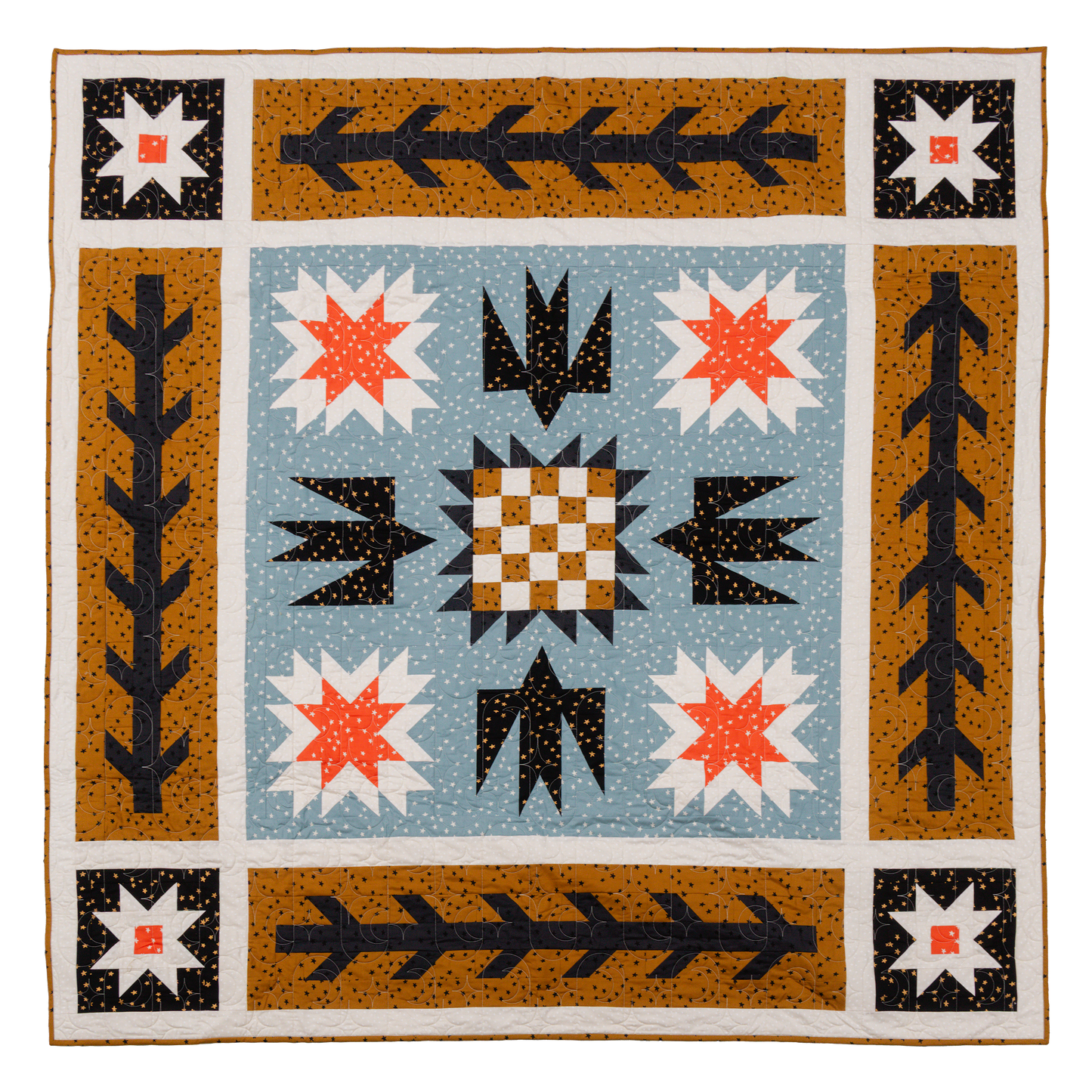 flat lay of geometric quilt featuring birds, stars, and checkerboard in warm tone fabrics with small star motif