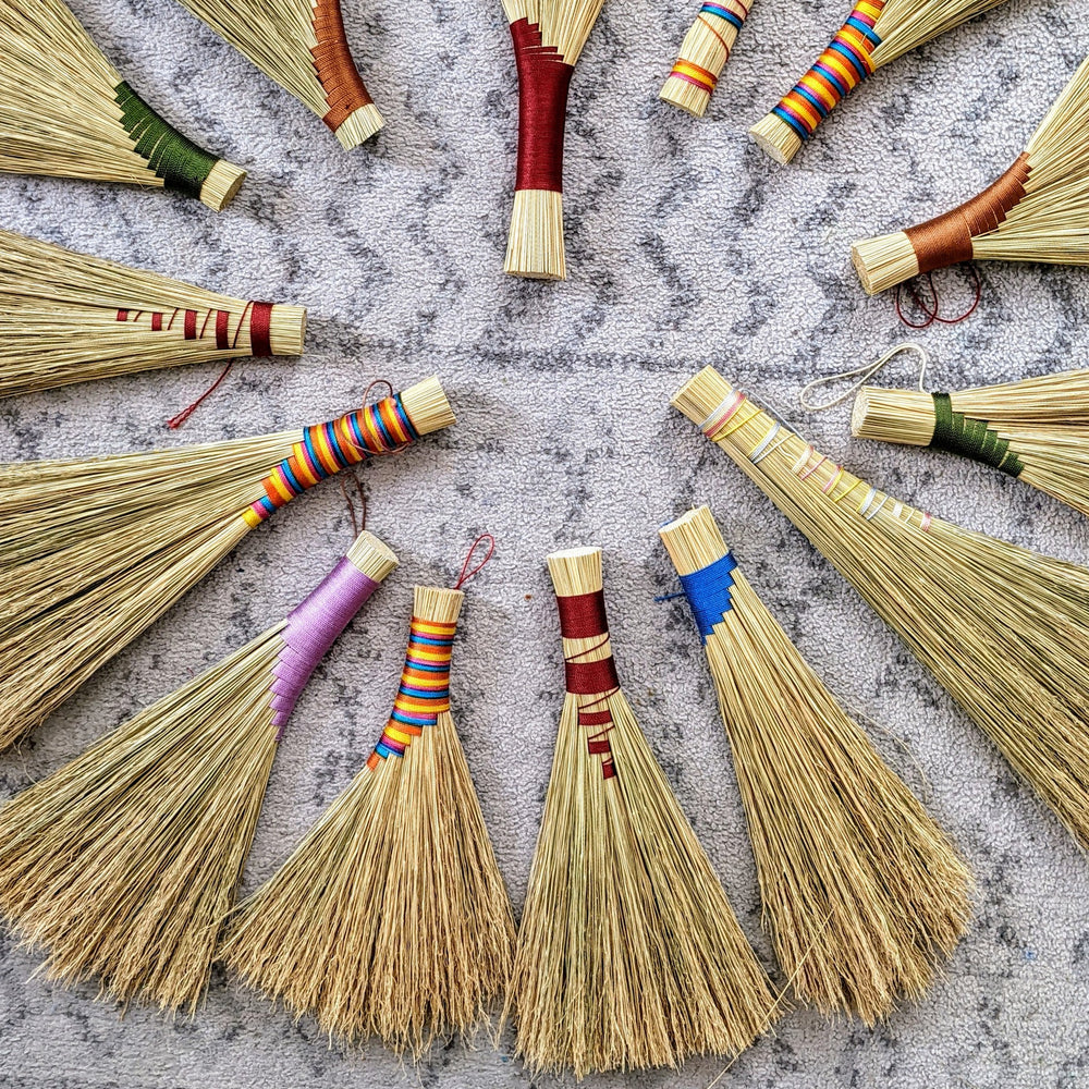 A circle display of straw hand brooms on a carpet, made at a crafting class at Wyldwood Creative Renton