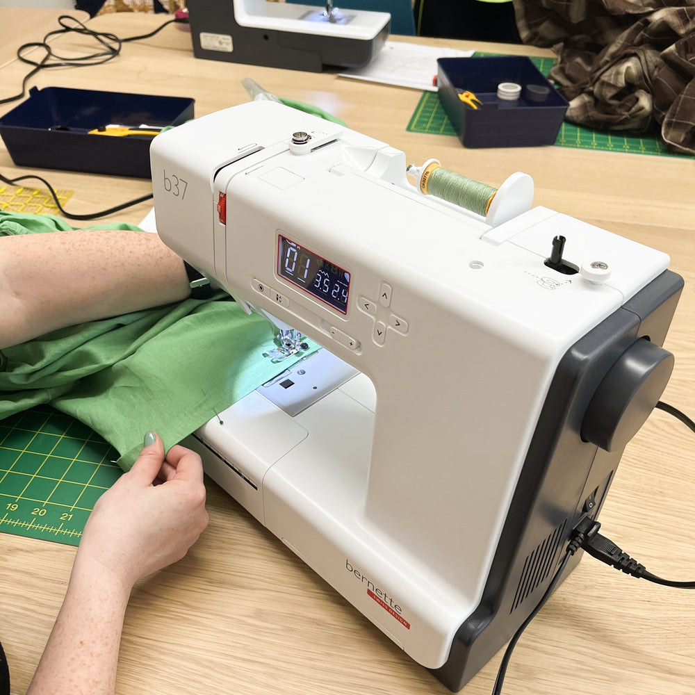 Close up of someone hemming some green fabric in a sewing machine during a hemming for beginners class at Wyldwood Creative in Renton