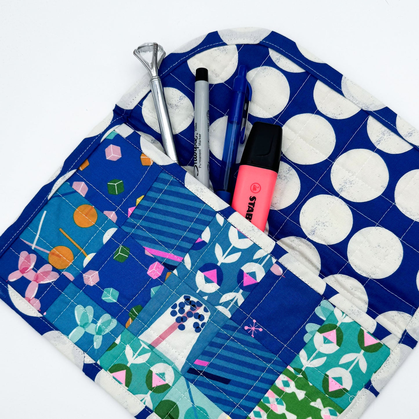 Multicolored quilted mini pouch opened up to show the size with pens and markers peeking out of the top - sewn in a beginner sewing class at Wyldwood Creative in Renton