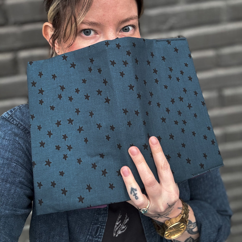 
                      
                        Tawnee holding open book over face to show the fabric book cover
                      
                    
