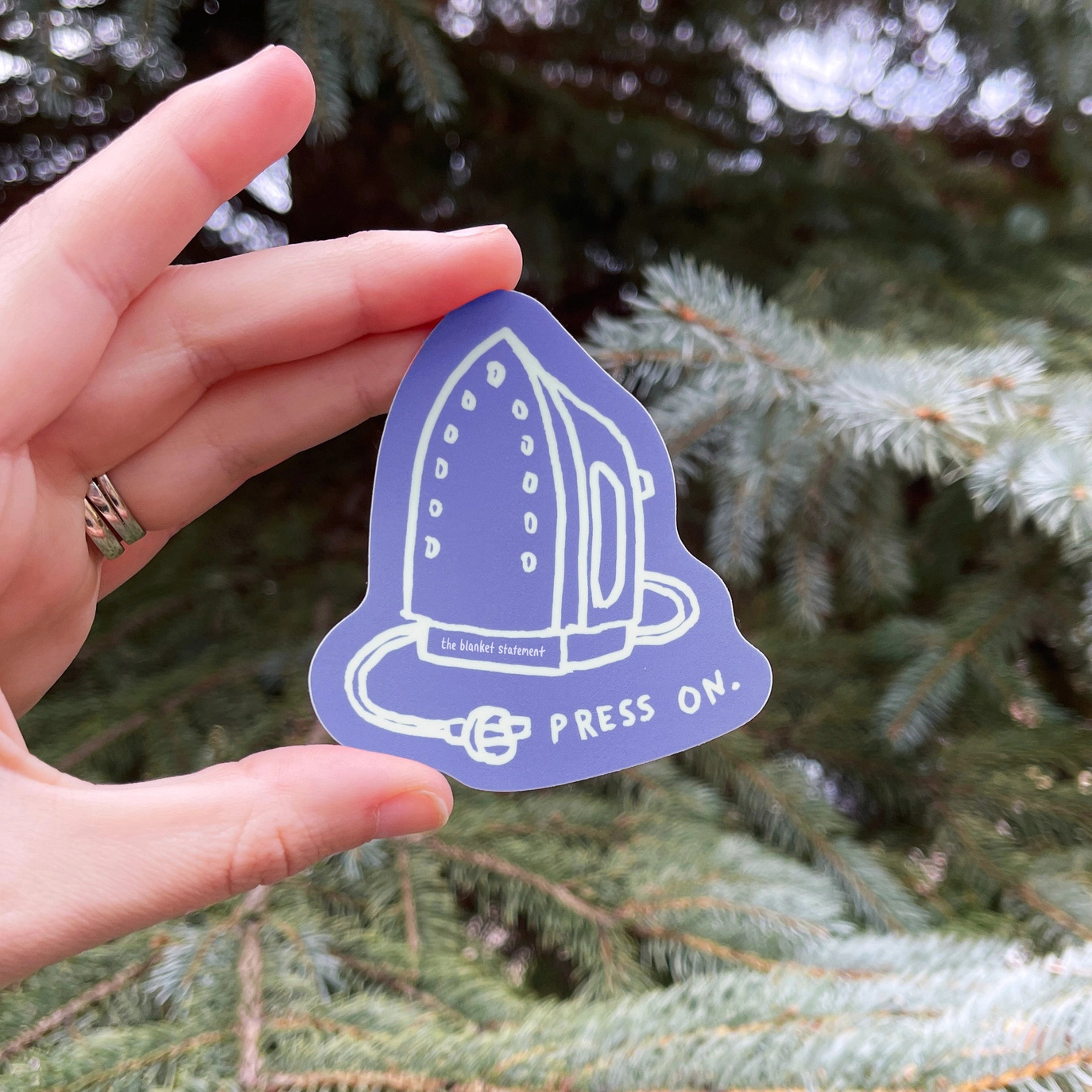 purple sticker featuring an iron and the words "press on"