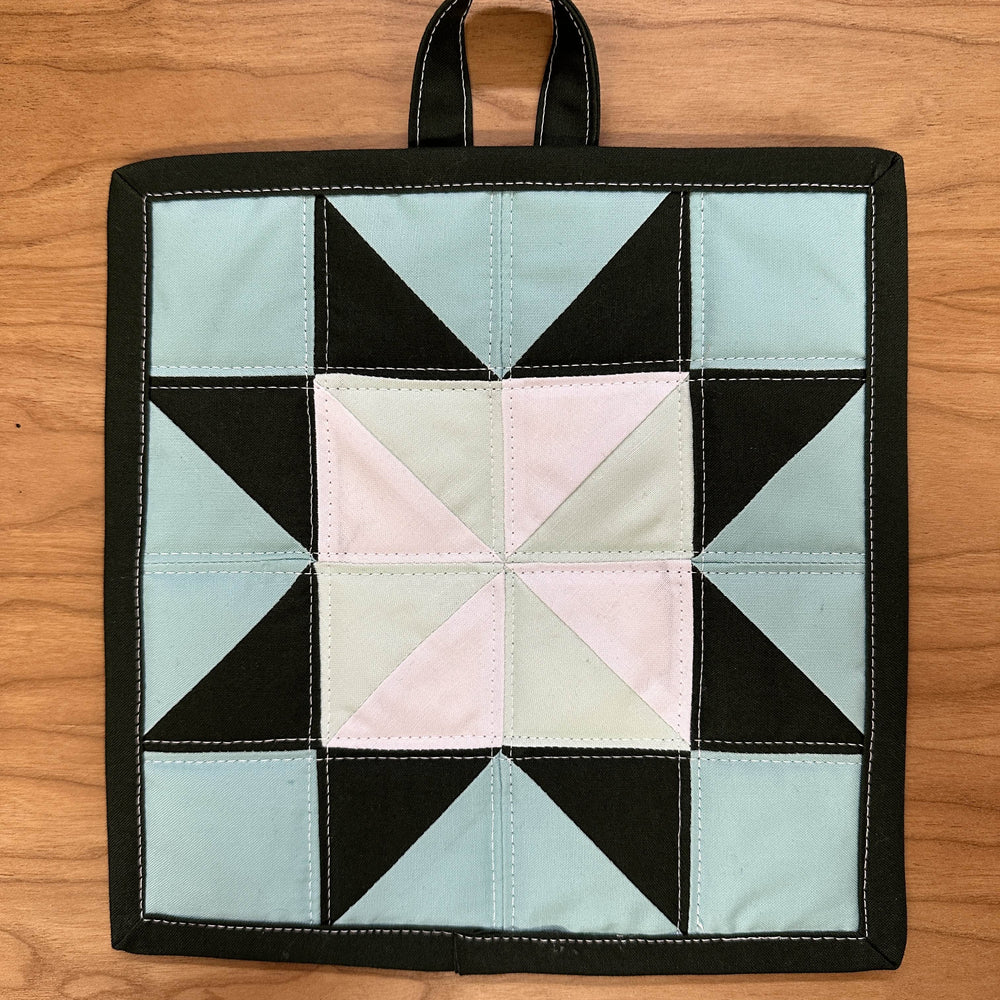 Quilted pot holder with geometric pattern on a wooden surface