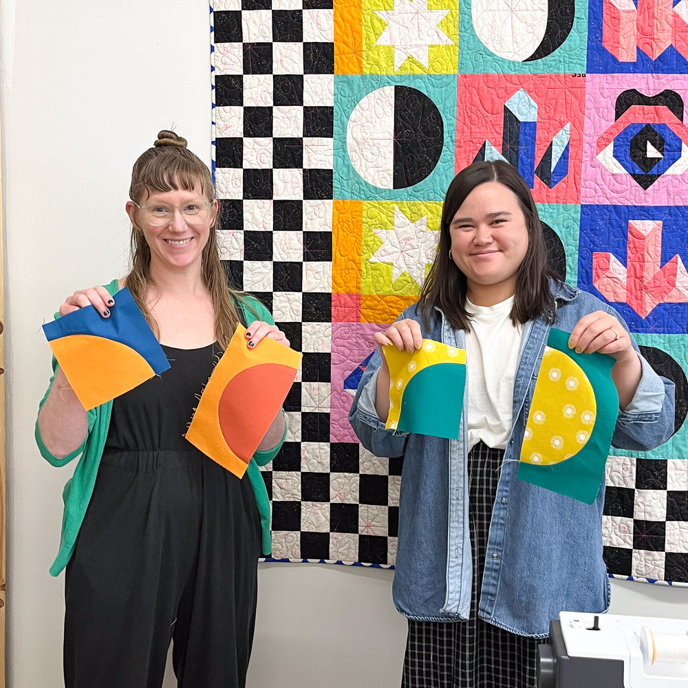 Two ladies holding up their sewn curves work in the quilting curves sewing class at Wyldwood Creative in Renton.