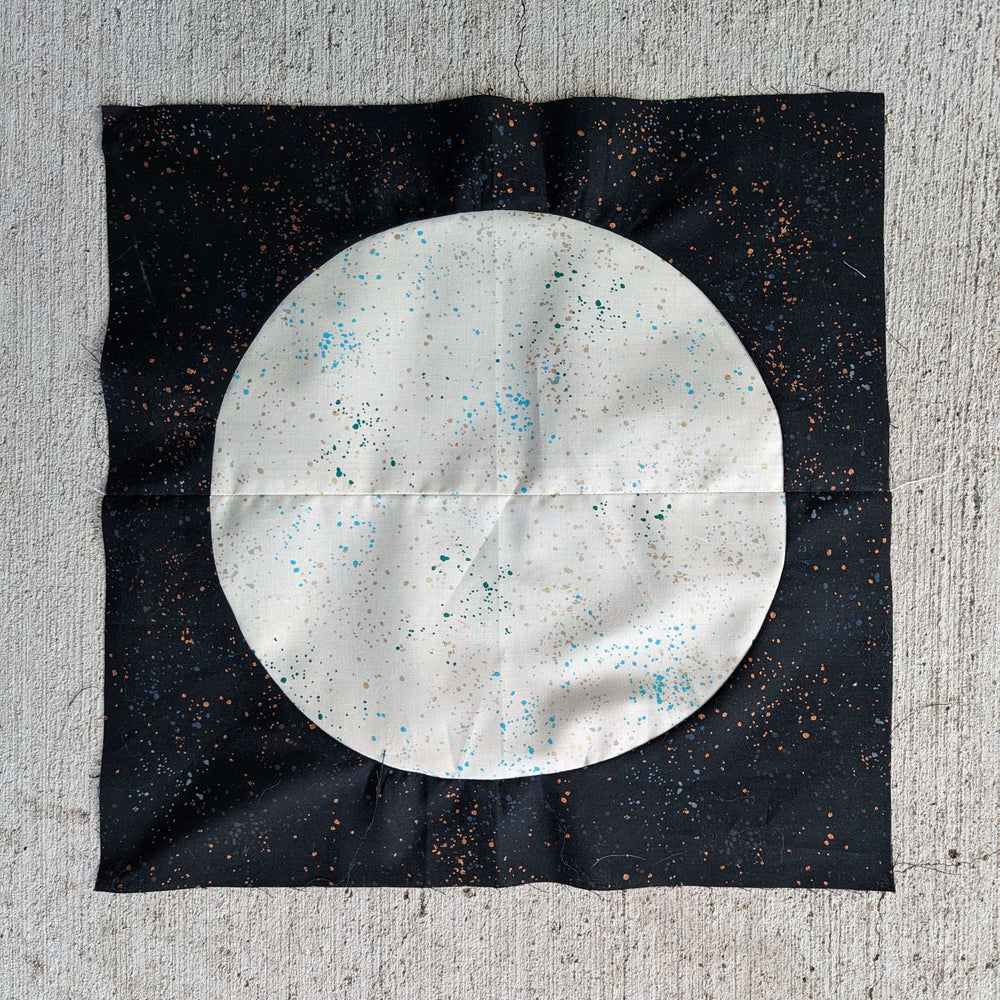 Black spotted fabric with a white spotted circle sewn to the center - like a moon - made of four quilting square pieces for a quilting curves class at Wyldwood Creative in Renton.