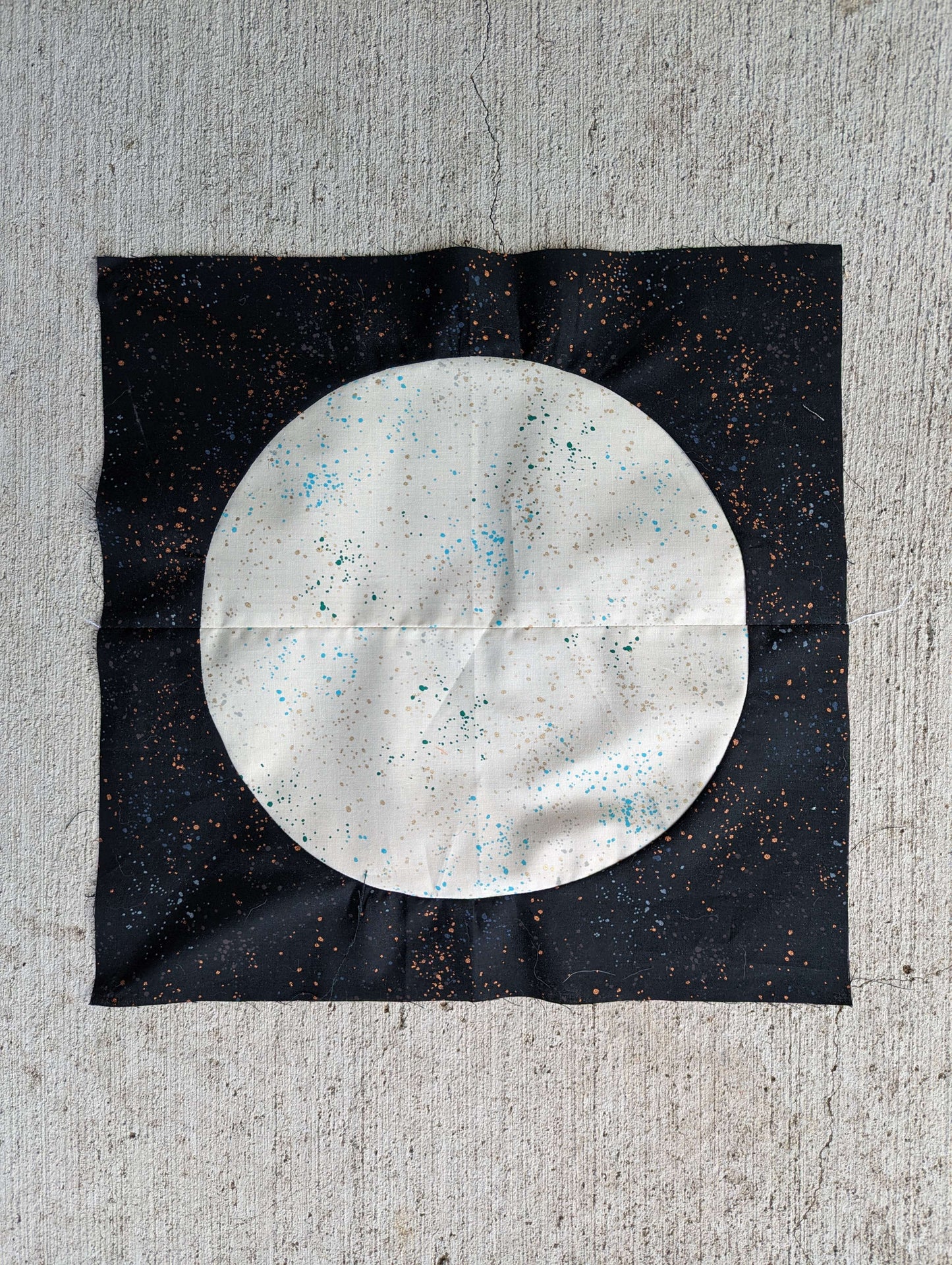 Black spotted fabric with a white spotted circle sewn to the center - like a moon - made of four quilting square pieces for a quilting curves class at Wyldwood Creative in Renton.