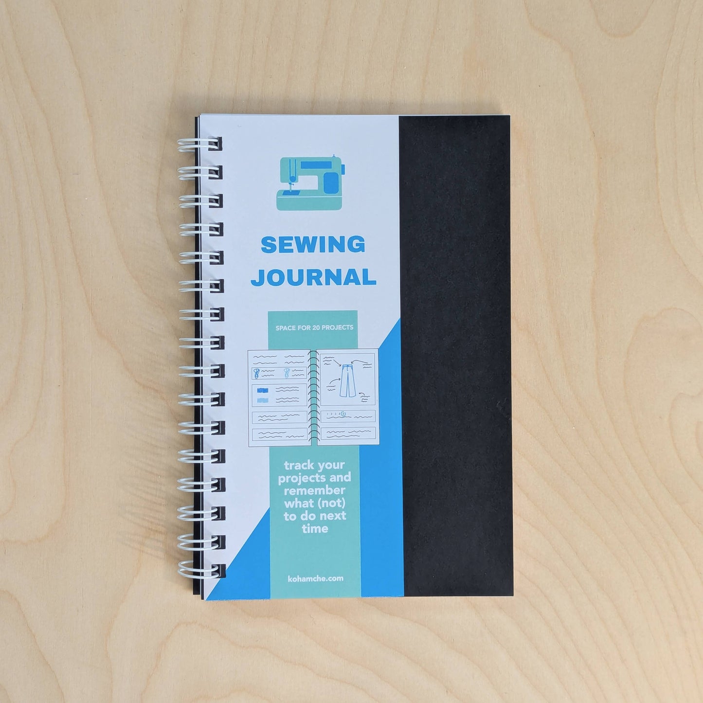 Sewing journal with black cover and blue spine on a wooden surface