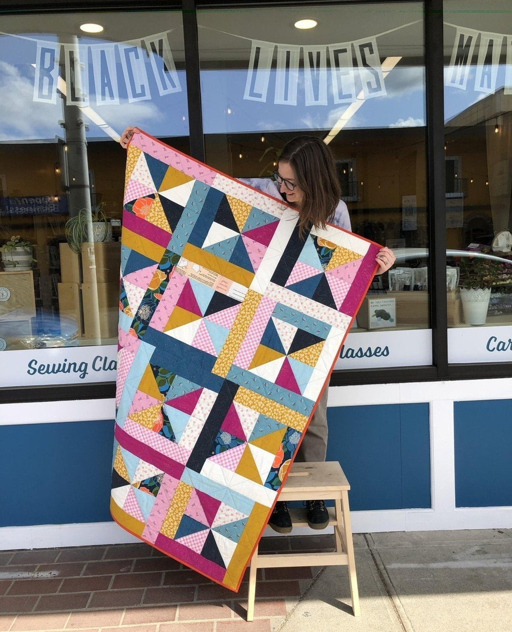 Tawnee holding up a finished Wyld Whirl Quilt made with this Digital Pattern