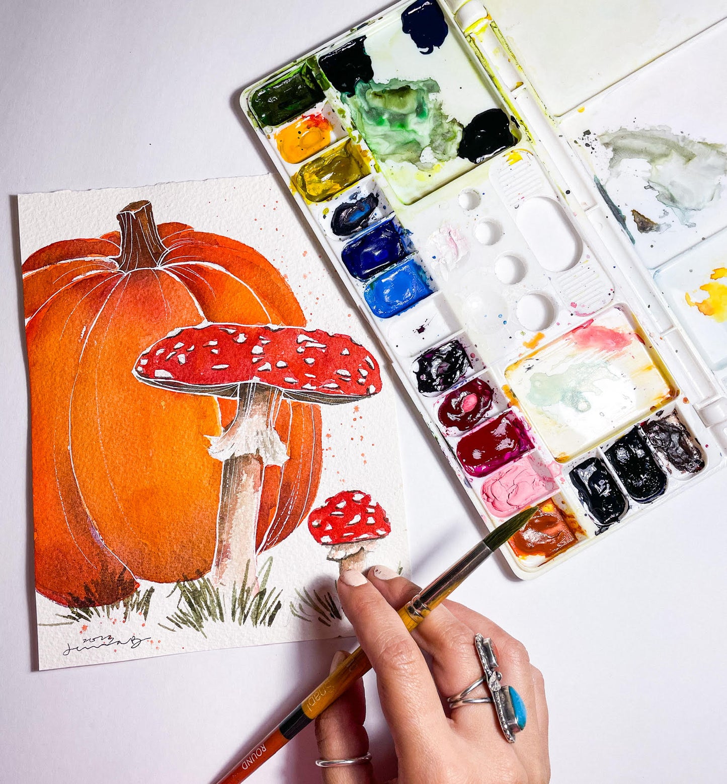 Someone doing a watercolor painting of a fall pumpkin and mushrooms at a watercoloring class at Wyldwood Creative in Renton.